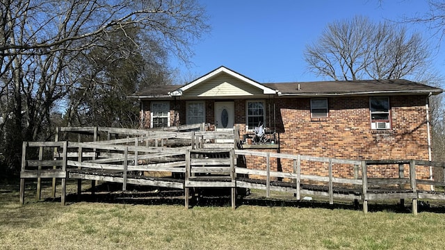 rear view of property featuring a yard, brick siding, a deck, and fence