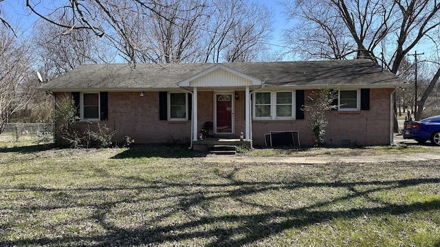 view of front facade with fence, roof with shingles, a front yard, crawl space, and brick siding