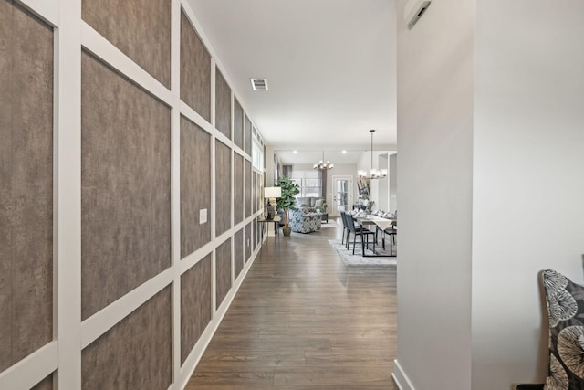 corridor featuring visible vents, an inviting chandelier, and dark wood-style floors