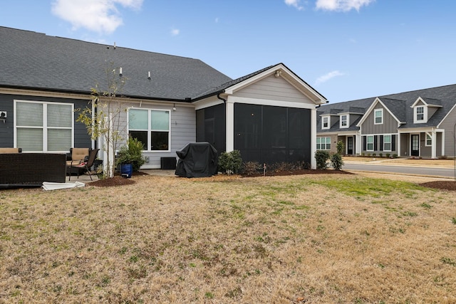 back of house with an outdoor living space, a yard, and a sunroom