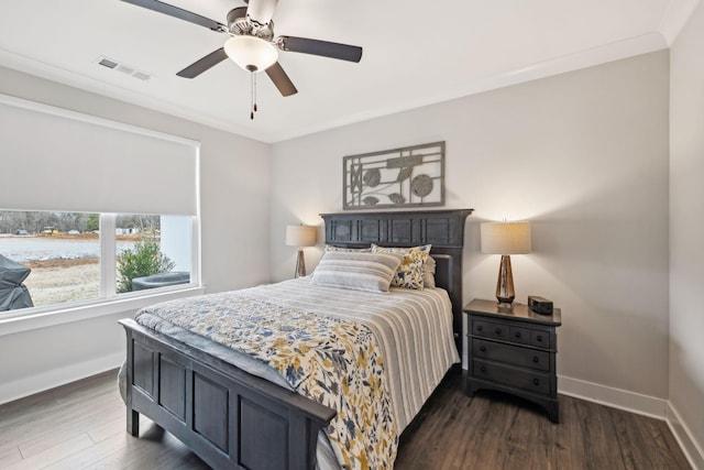 bedroom featuring visible vents, baseboards, dark wood finished floors, and ornamental molding