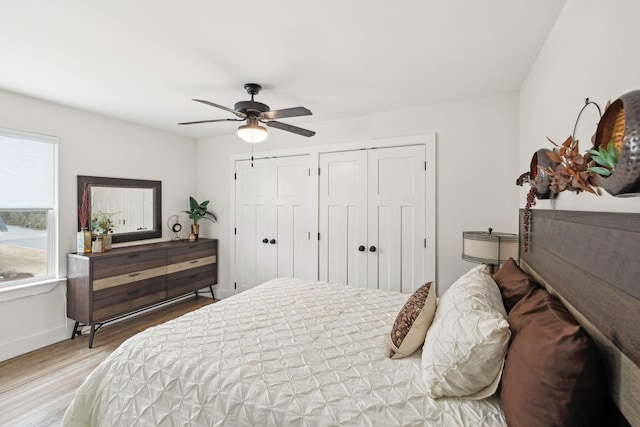 bedroom with wood finished floors, baseboards, two closets, and ceiling fan