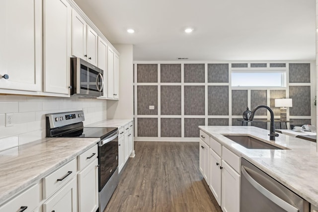 kitchen with a sink, tasteful backsplash, stainless steel appliances, white cabinets, and dark wood-style flooring