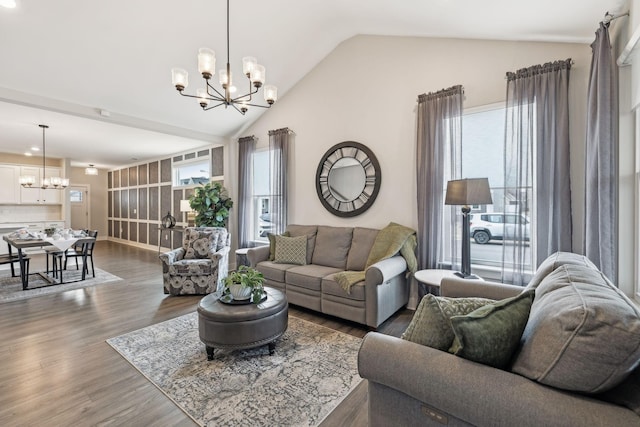 living room featuring lofted ceiling, an inviting chandelier, wood finished floors, and a wealth of natural light