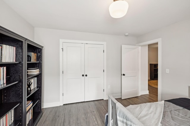 bedroom with wood finished floors, a closet, and baseboards