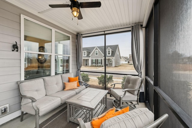 sunroom / solarium featuring a residential view, a healthy amount of sunlight, and a ceiling fan