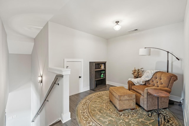 sitting room with visible vents, an upstairs landing, baseboards, and wood finished floors