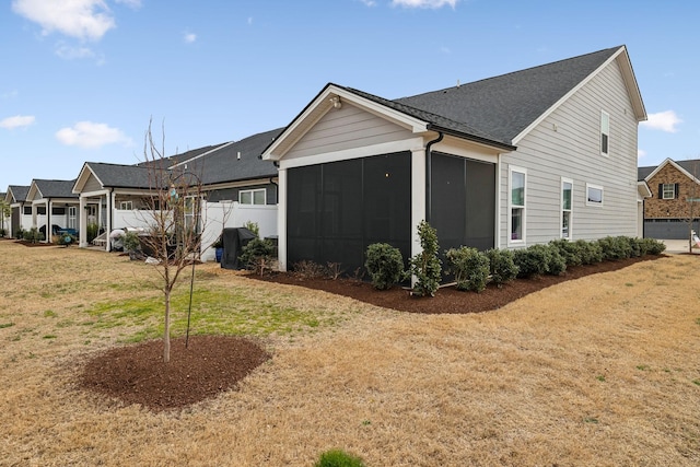 view of front facade featuring a residential view, fence, a front yard, and a sunroom