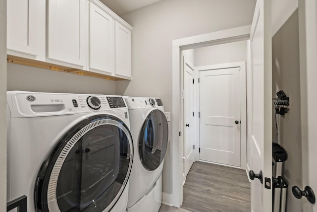 washroom featuring cabinet space, washing machine and dryer, and light wood finished floors