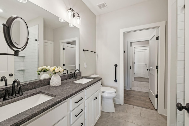 bathroom with tile patterned flooring, visible vents, toilet, and a sink