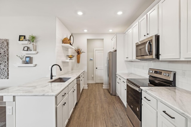 kitchen featuring open shelves, a sink, decorative backsplash, stainless steel appliances, and white cabinets