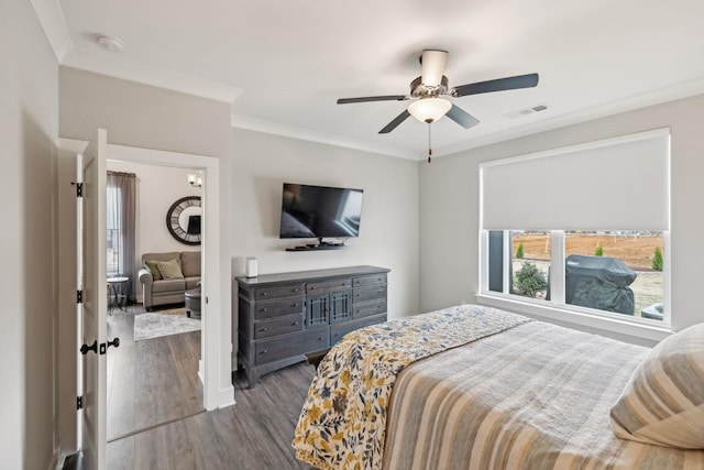 bedroom with visible vents, ornamental molding, ceiling fan, and wood finished floors