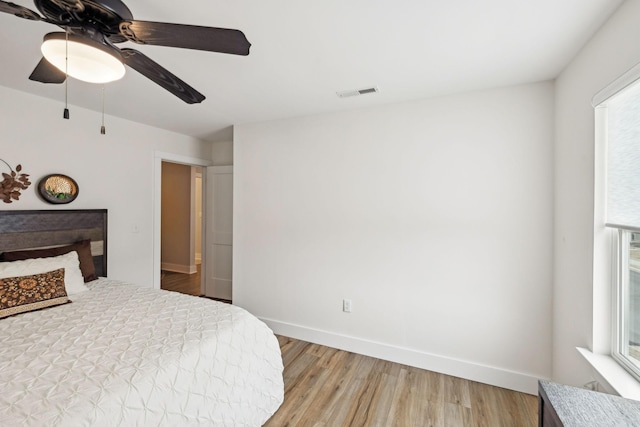 bedroom featuring visible vents, baseboards, multiple windows, and light wood finished floors