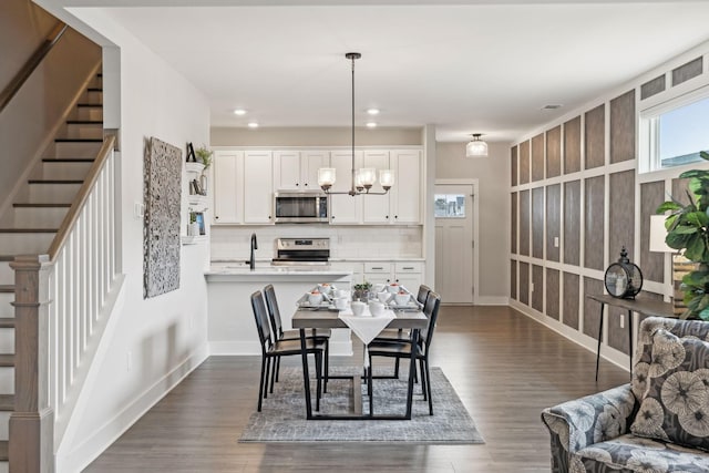 dining space featuring stairway, an inviting chandelier, and dark wood-style floors