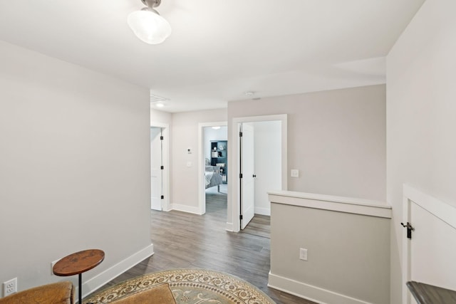 corridor featuring dark wood-type flooring and baseboards