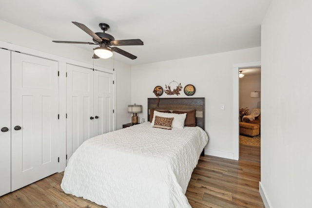 bedroom with ceiling fan, baseboards, multiple closets, and wood finished floors