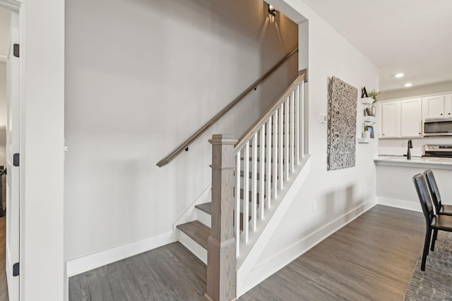 stairway with recessed lighting, wood finished floors, and baseboards