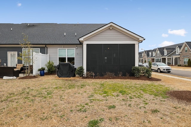 back of house with a residential view, a yard, and a sunroom