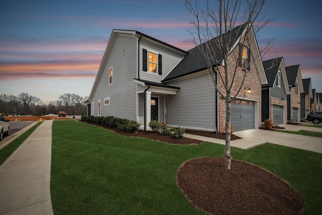 traditional-style home with brick siding, a garage, a lawn, and driveway