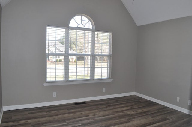 unfurnished room with visible vents, plenty of natural light, lofted ceiling, and dark wood finished floors