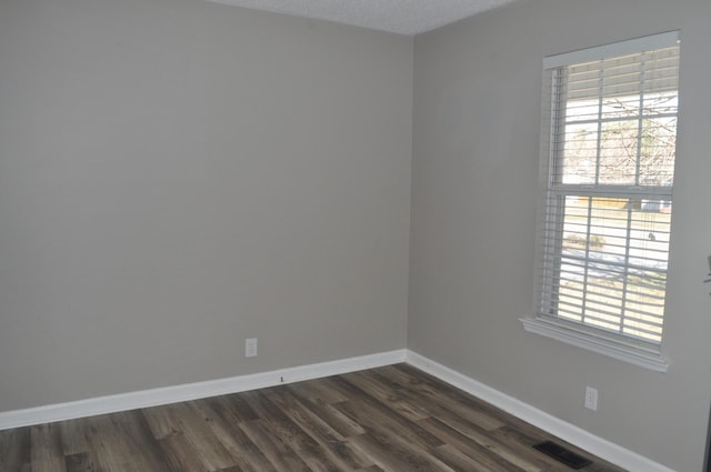 spare room with dark wood-type flooring, baseboards, a wealth of natural light, and a textured ceiling