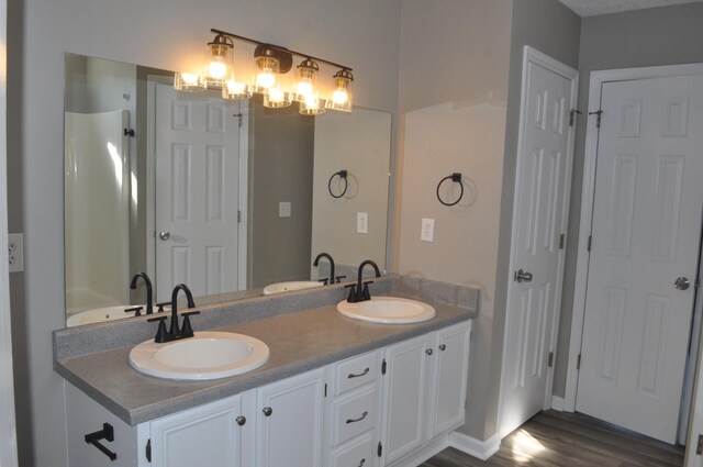 full bathroom with double vanity, wood finished floors, and a sink