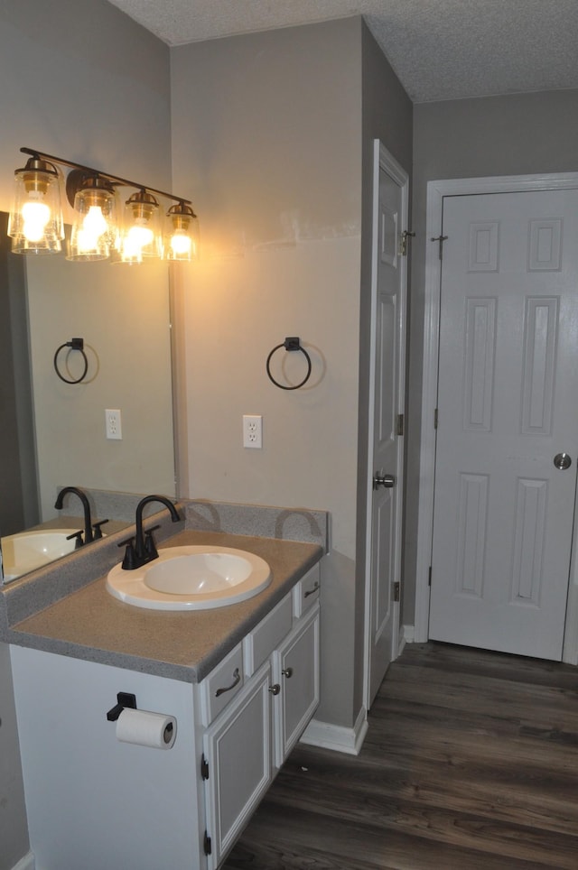 bathroom with baseboards, a textured ceiling, wood finished floors, and vanity