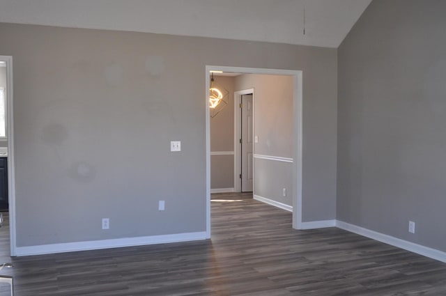 empty room featuring baseboards and dark wood-type flooring