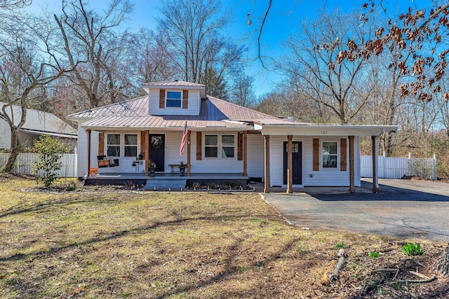 view of front of house featuring driveway, a front lawn, fence, covered porch, and metal roof