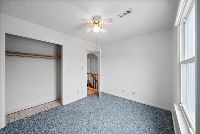 unfurnished bedroom with visible vents, baseboards, a closet, a textured ceiling, and a ceiling fan