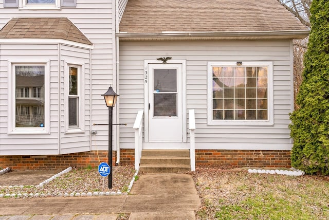 entrance to property featuring roof with shingles