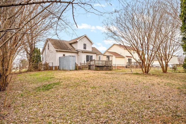 rear view of house featuring a yard, a deck, and fence