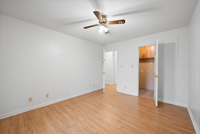 unfurnished bedroom featuring baseboards, a textured ceiling, ceiling fan, and light wood finished floors