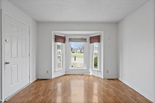 doorway to outside with a textured ceiling, baseboards, and wood finished floors