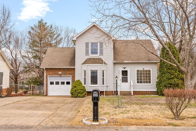 traditional-style house featuring entry steps, fence, concrete driveway, a shingled roof, and a garage