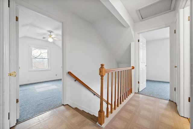 hallway with tile patterned floors, an upstairs landing, carpet floors, and attic access