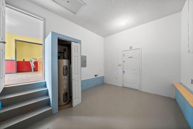 corridor with a textured ceiling, electric panel, concrete flooring, and electric water heater