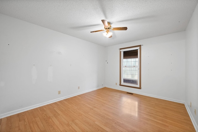 empty room with baseboards, visible vents, ceiling fan, a textured ceiling, and light wood-type flooring