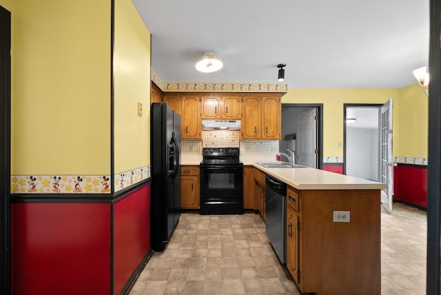 kitchen featuring under cabinet range hood, a peninsula, brown cabinetry, black appliances, and a sink