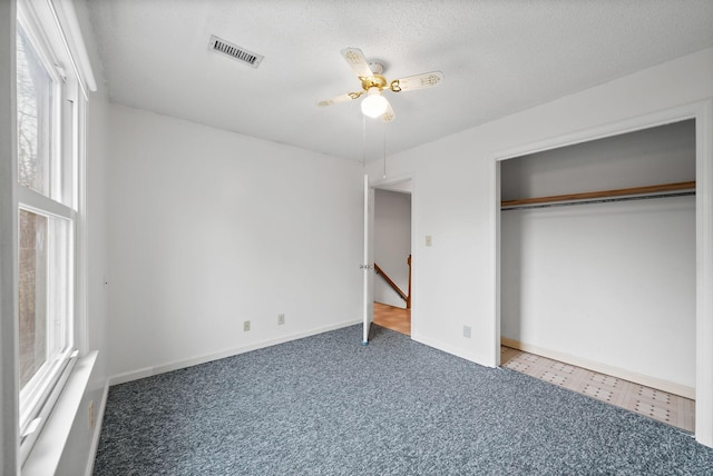 unfurnished bedroom featuring visible vents, baseboards, carpet, a closet, and a textured ceiling