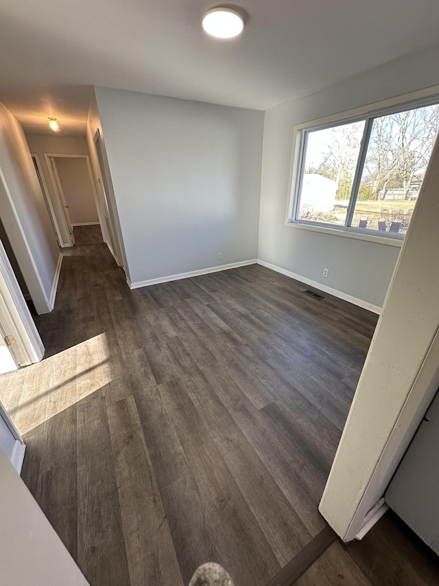 unfurnished room featuring visible vents, baseboards, and dark wood-style floors