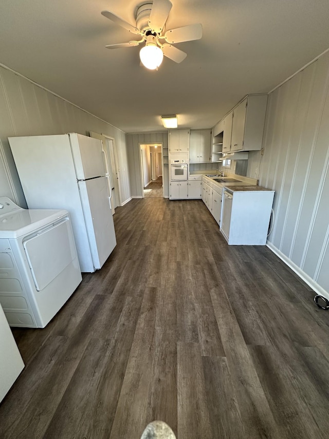 kitchen featuring dark wood-type flooring, washer / clothes dryer, white appliances, white cabinets, and ceiling fan