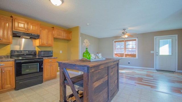 kitchen with light floors, baseboards, black appliances, under cabinet range hood, and dark countertops