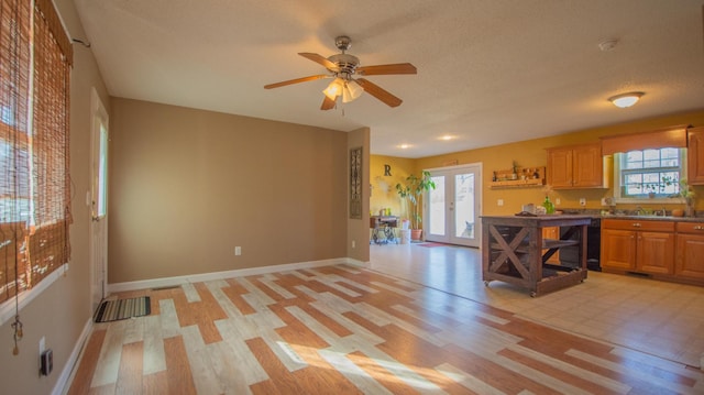 kitchen with french doors, plenty of natural light, light wood-style floors, and baseboards