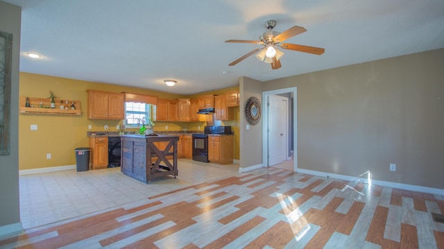 kitchen with black appliances, under cabinet range hood, open floor plan, a center island, and baseboards