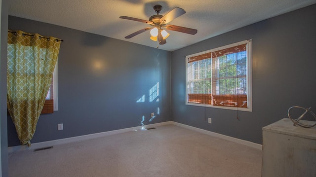 empty room with visible vents, a ceiling fan, a textured ceiling, carpet, and baseboards