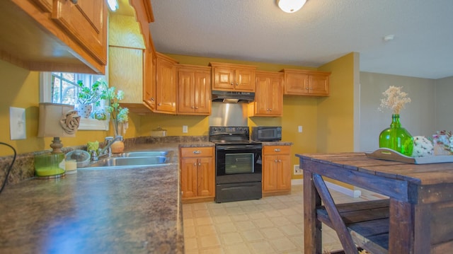 kitchen with black appliances, under cabinet range hood, a sink, dark countertops, and light floors