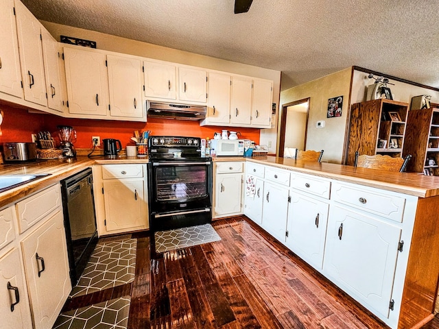 kitchen featuring dark wood-type flooring, under cabinet range hood, a peninsula, a textured ceiling, and black appliances