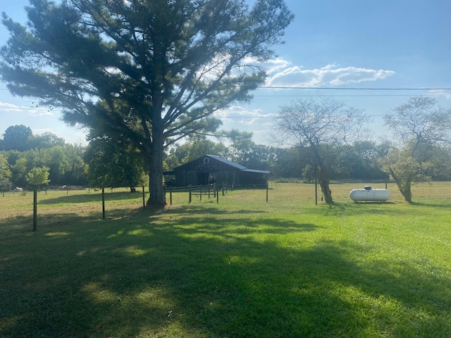 view of yard with a rural view, fence, an outdoor structure, and a pole building