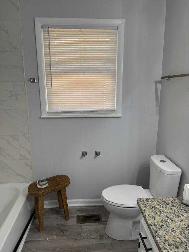 bathroom with visible vents, baseboards, toilet, wood finished floors, and vanity
